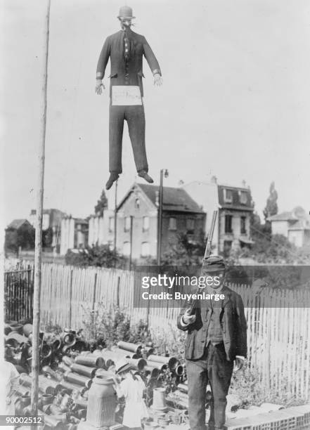 An old man carrying a rifle guards a hanging effigy of Kaiser Wilhelm of Germany