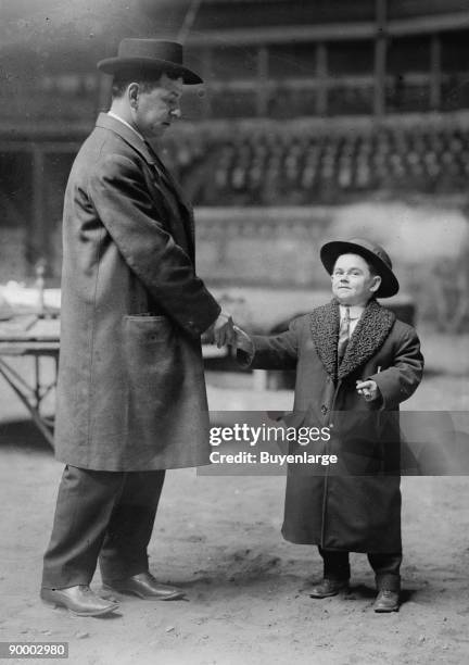 Jack Barrett, circus Midgit with lambs wool collared overcoat and chomping on a huge cigar shakes hand with full-sized man in the Circus area being...