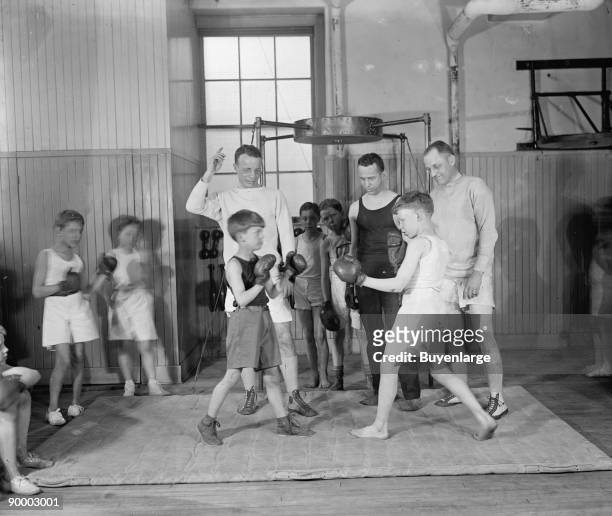 Theodore Roosevelt 3rd as a young boy gets boxing instruction at a gym for young ones like himself.