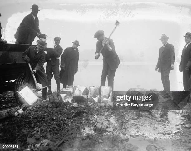 Police take axes & Picks to canisters of illegal alcohol during prohibition