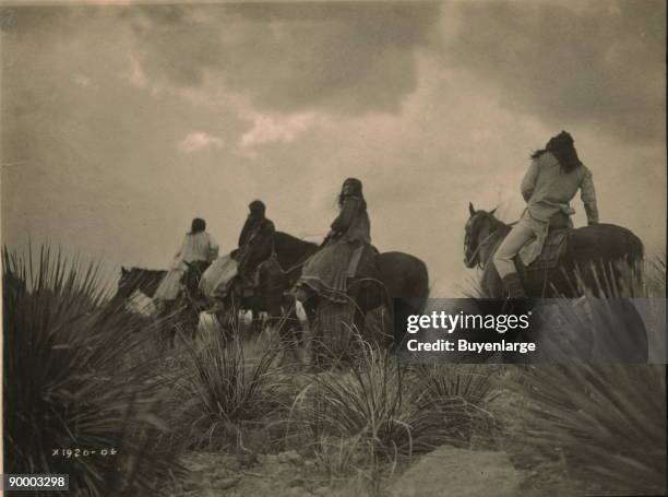 Four Apaches on horseback under storm clouds.