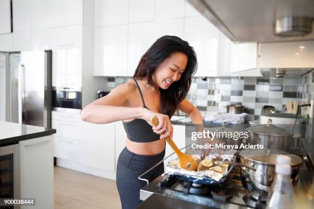 fit asian woman in yoga clothes cooking in modern apartment - gas stove cooking stock pictures, royalty-free photos & images