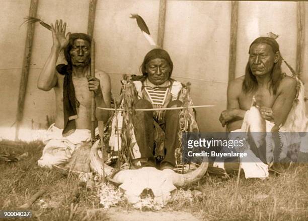 Three Native Americans, Slow Bull, Saliva, and Picket Pin, kneeling with bison skull.