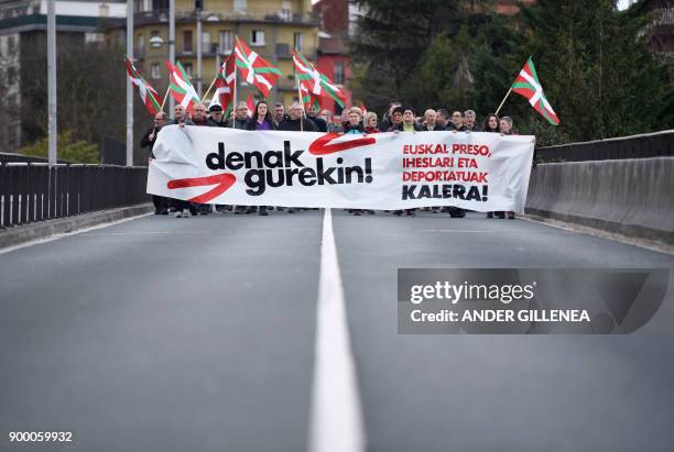 People holding Basque flags and a banner reading "All of them with us, Basque prisoners and exiles" march from the Spanish Basque village of Hernani...