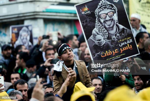 Supporters of the Fatah movement hold up a portrait of late Palestinian leader Yasser Arafat during a rally in Gaza City on December 31 marking the...
