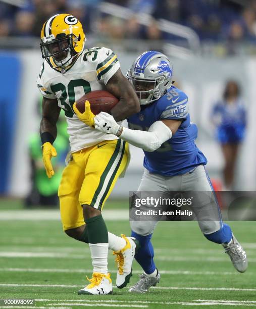 Jamaal Williams of the Green Bay Packers runs with the ball against Jamal Agnew of the Detroit Lions during the first half at Ford Field on December...