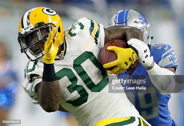 Jamaal Williams of the Green Bay Packers runs with the ball against Jamal Agnew of the Detroit Lions during the first half at Ford Field on December...