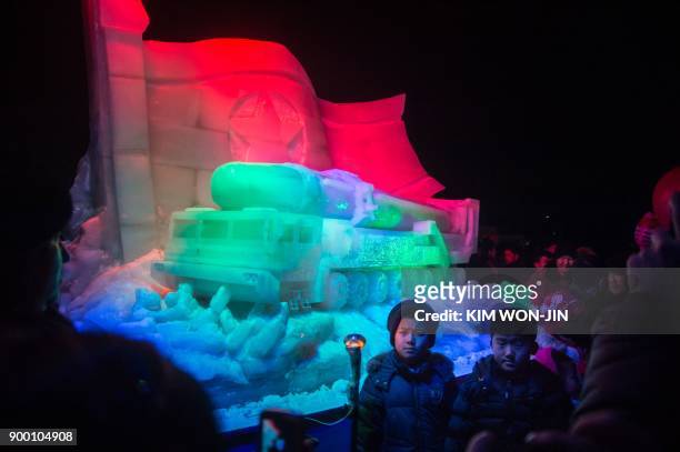 Children pose for a photo before an ice sculpture depicting a Hwasong-15 intercontinental ballistic missile and self-propelled launcher, as people...