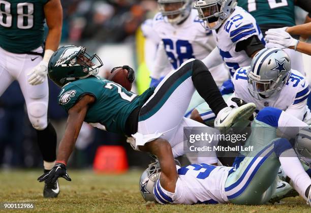 Running back Wendell Smallwood of the Philadelphia Eagles is tackled by cornerback Chidobe Awuzie and free safety Byron Jones of the Dallas Cowboys...