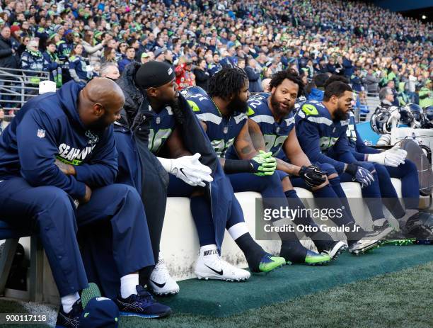 Defensive end Michael Bennett of the Seattle Seahawks, facing, talks with Sheldon Richardson as they sit on the bench during the national anthem...