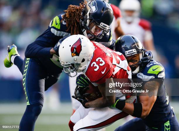 Running back Kerwynn Williams of the Arizona Cardinals is tackled by cornerback Shaquill Griffin of the Seattle Seahawks and Earl Thomas in the first...