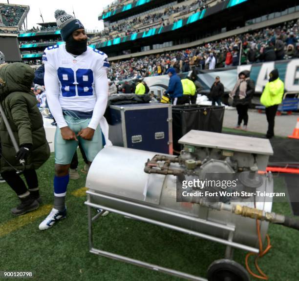 Standing next to a large gas heater, Dallas Cowboys wide receiver Dez Bryant tries to stay warm on the sidelines against the Philadelphia Eagles at...