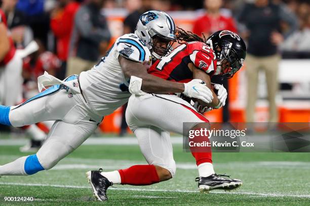 Devonta Freeman of the Atlanta Falcons is tackled by Thomas Davis of the Carolina Panthers during the first half at Mercedes-Benz Stadium on December...