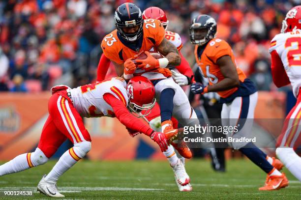 Running back Devontae Booker of the Denver Broncos is hit by defensive back Leon III McQuay of the Kansas City Chiefs at Sports Authority Field at...