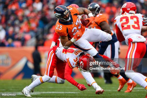 Running back Devontae Booker of the Denver Broncos is hit by defensive back Leon III McQuay of the Kansas City Chiefs at Sports Authority Field at...