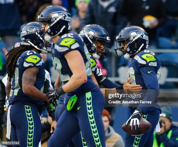 Quarterback Russell Wilson of the Seattle Seahawks greets Doug Baldwin after Baldwin brought in an 18 yard touchdown against the Arizona Cardinals in...