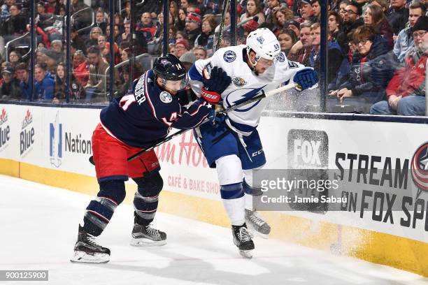 Jordan Schroeder of the Columbus Blue Jackets and Jake Dotchin of the Tampa Bay Lightning battle for a loose puck during the first period of a game...