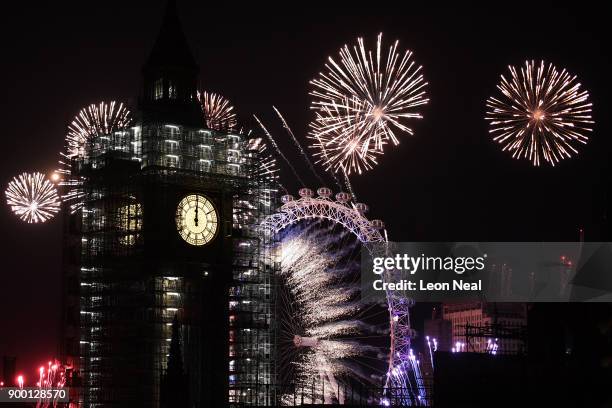 Fireworks explode over Big Ben and the giant Ferris wheel of the London Eye at midnight as thousands gather to ring in the near year on January 1,...