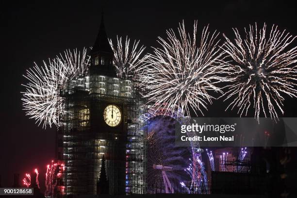 Fireworks explode over Big Ben and the giant Ferris wheel of the London Eye at midnight as thousands gather to ring in the near year on January 1,...