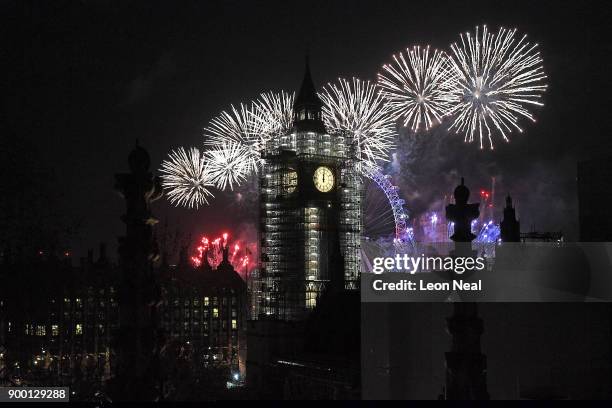 Fireworks explode over Big Ben and the giant Ferris wheel of the London Eye at midnight as thousands gather to ring in the near year on January 1,...