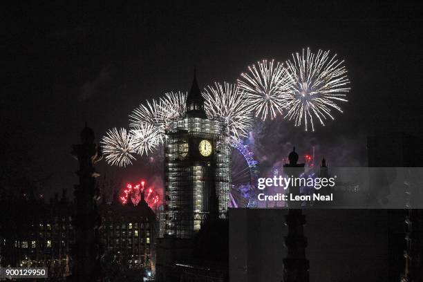 Fireworks explode over Big Ben and the giant Ferris wheel of the London Eye at midnight as thousands gather to ring in the near year on January 1,...