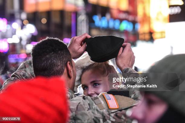 Man puts his hat on a woman's head in Times Square ahead of the New Year's Eve celebration on December 31, 2017 in New York City.