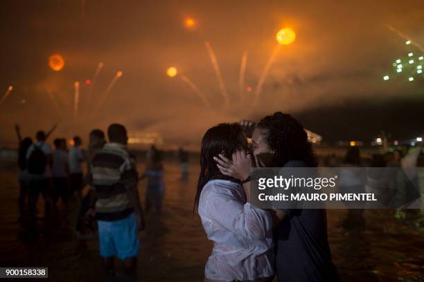 People kiss as fireworks go off during New Year's celebrations at Copacabana beach in Rio de Janeiro on January 1, 2018. / AFP PHOTO / MAURO PIMENTEL