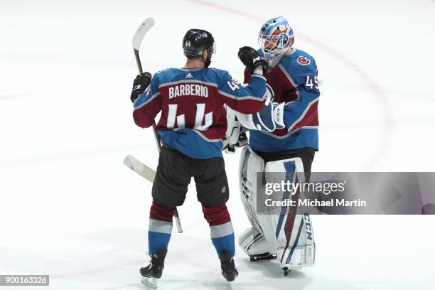 Goaltender Jonathan Bernier of the Colorado Avalanche celebrates a win against the New York Islanders with teammate Mark Barberio at the Pepsi Center...