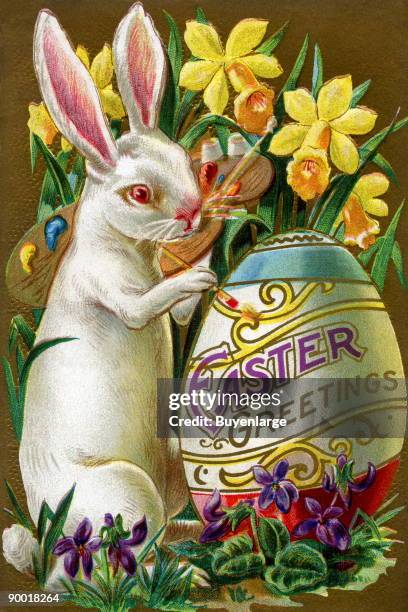 An Easter bunny rabbit paints an Easter Greetings egg within a flower garden.