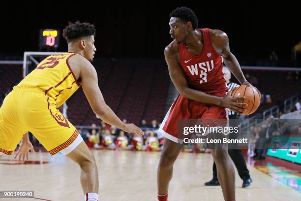 Robert Franks of the Washington State Cougars handles the ball against Bennie Boatwright of the USC Trojans during a PAC12 college basketball game at...