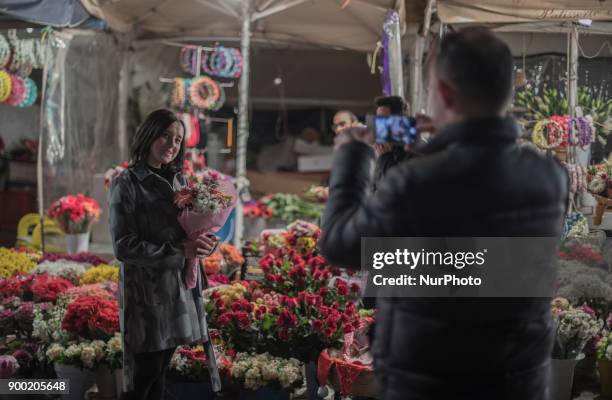 Woman takes pictures beside a flower shop in Taksim Square in Istanbul on the last night in 2017