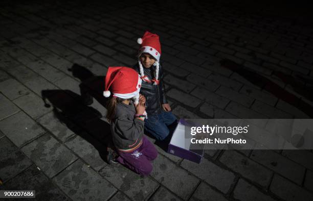 Children of Syrian refugees wearing a Santa Claus hat sitting in the middle of the street to beg during the New Year 2018