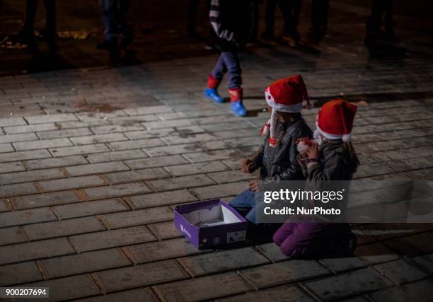 Children of Syrian refugees wearing a Santa Claus hat sitting in the middle of the street to beg during the New Year 2018