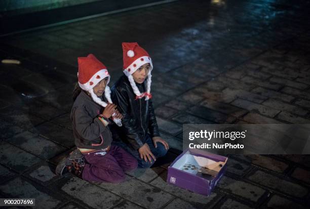 Children of Syrian refugees wearing a Santa Claus hat sitting in the middle of the street to beg during the New Year 2018