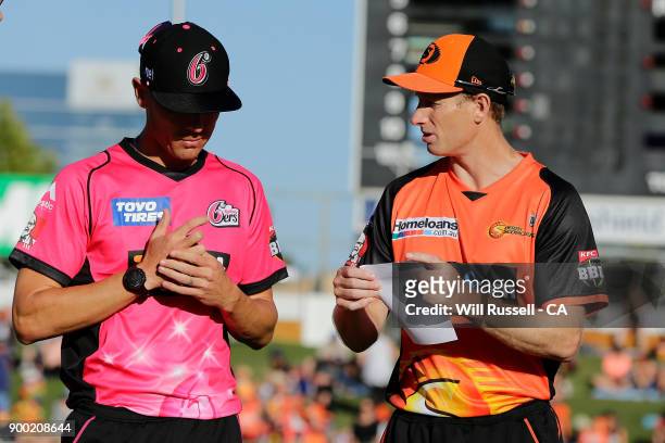 Moises Henriques of the Sixers and Adam Voges of the Scorchers exchange team sheets during the Big Bash League match between the Perth Scorchers and...