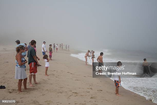 Beachgoers watch large waves crash on Lighthouse Beach though the ocean is closed to swimming on August 22, 2009 in Chatham, Massachusetts. A strong...
