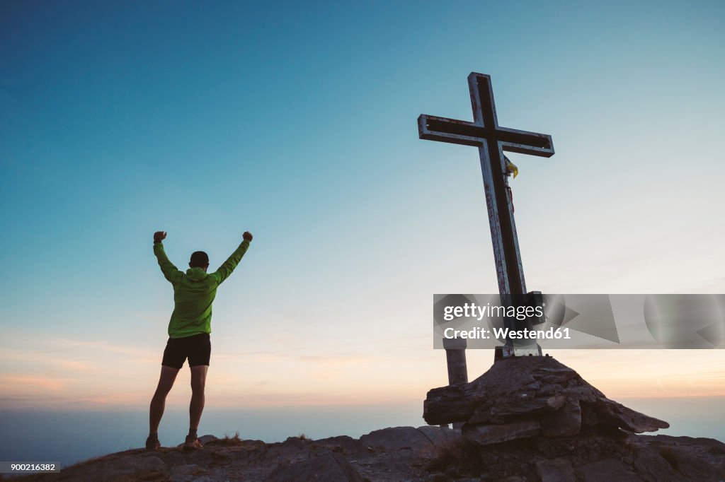 Italy, mountain running man cheering next to summit cross