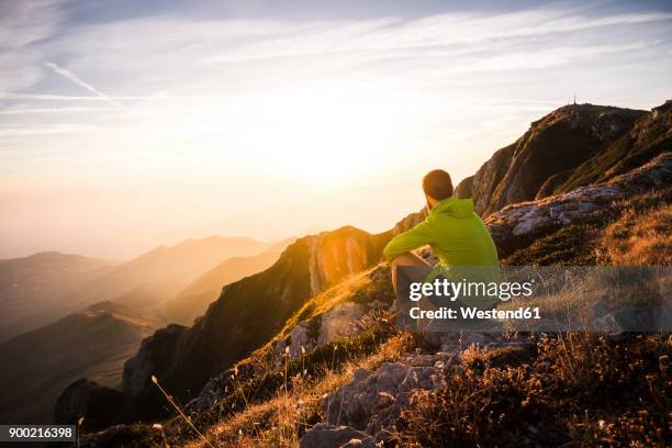 italy, mountain running man sitting on rock looking at sunset - outdoor guy sitting on a rock stock pictures, royalty-free photos & images