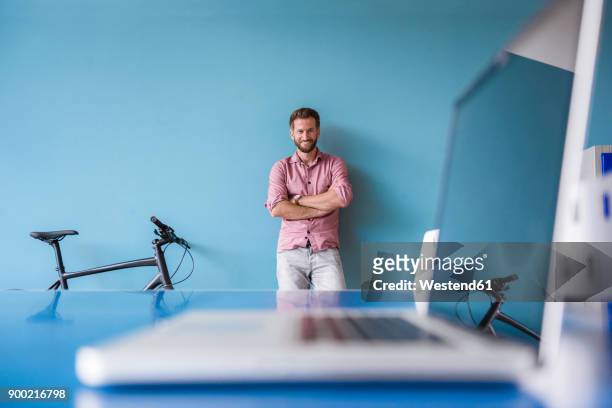 portrait of smiling man and laptop in break room of modern office - focus on background stock pictures, royalty-free photos & images