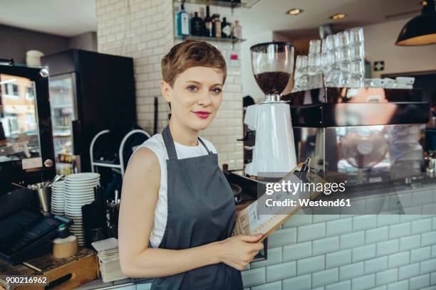 portrait of waitress holding menu in a cafe - kellnerin stock-fotos und bilder