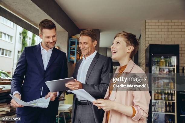 woman and two businessmen discussing plans in a cafe - businessman looking at map stock pictures, royalty-free photos & images