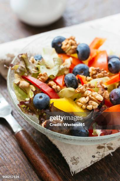 glass bowl of mixed salad with different raw vegetables, blueberries and walnuts - schist stock-fotos und bilder