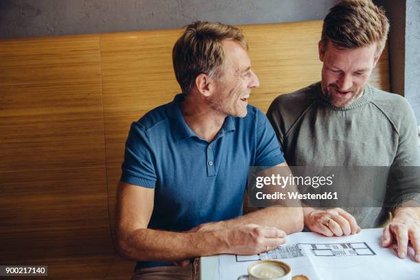 happy gay couple looking at constructions plans for their home in cafe - leisure work coffee happy stockfoto's en -beelden