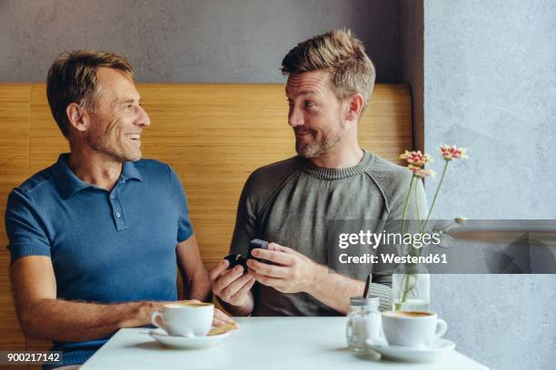 gay man offering wedding ring to partner in cafe - speaking engagement stock pictures, royalty-free photos & images