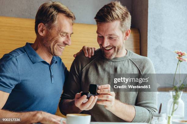 excited gay couple with wedding ring in cafe - team engagement stock pictures, royalty-free photos & images