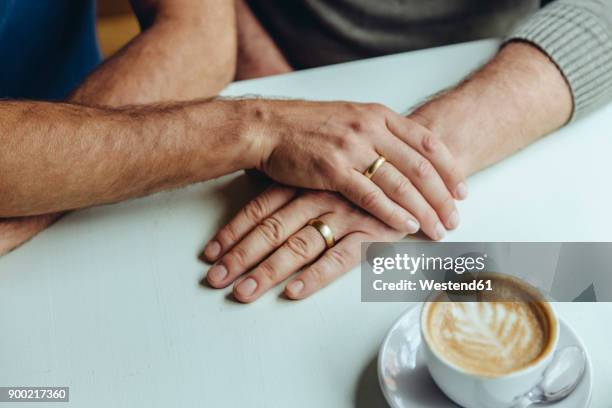 close-up of men's hands with wedding rings and a cup of coffee - fede nuziale foto e immagini stock