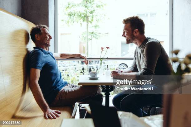 Two men sitting in cafe talking to one another