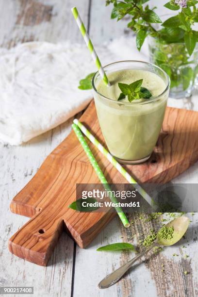 glass of green smoothie with coconut milk, banana, matcha powder garnished with mint leaves - green coconut stock-fotos und bilder