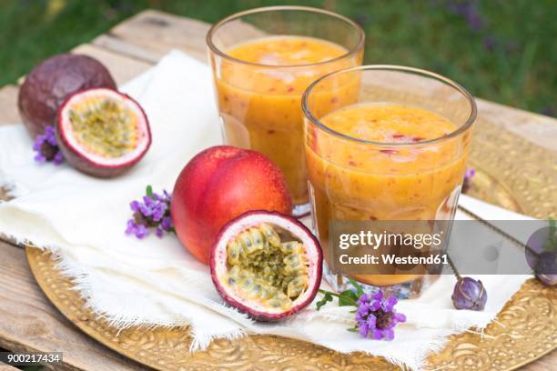 two glasses of fruit smoothie with passion fruit, nectarine, pomegranate juice and rice milk - nectarine stockfoto's en -beelden