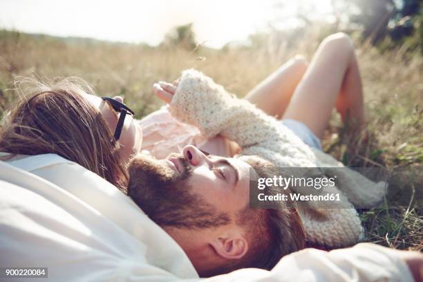 happy young couple lying in grass - women lying stock-fotos und bilder